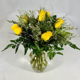 Yellow roses in a clear glass vase with airy greenery