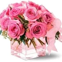 Pink roses arranged in a clear square vase with a pink ribbon