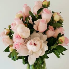 Bouquet of pale pink roses and white peonies in a clear glass vase