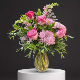 Pink roses and lavender chrysanthemums in a clear glass vase