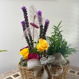 Basket arrangement with yellow and pink roses and purple spikes
