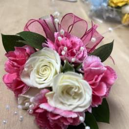 Pink and white floral corsage with ribbon and pearl accents