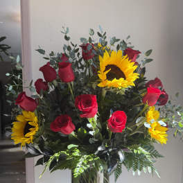 Bouquet of red roses and sunflowers in a glass vase