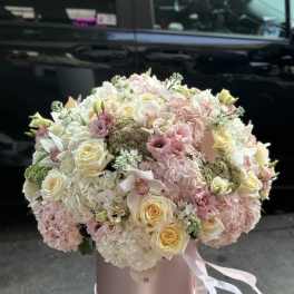 Large pastel bouquet of roses, hydrangeas, and orchids in a pink hat box