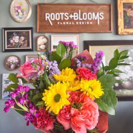Handheld bouquet of pink, yellow, and coral flowers
