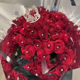 Bouquet of red roses wrapped in silver paper with a jeweled crown
