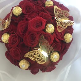 Bouquet of red roses with gold-wrapped chocolates and butterfly decorations