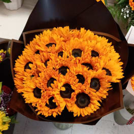 Bouquet of orange sunflowers wrapped in dark paper