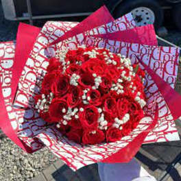 Bouquet of red roses with white baby's breath in patterned red-and-white wrap