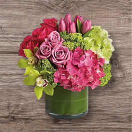 Pink roses, tulips, and hydrangeas arranged in a green glass vase