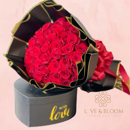 Bouquet of red roses in black and gold wrapping with a gift box