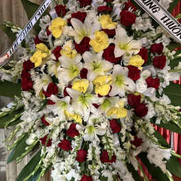 Large funeral wreath of red roses, white lilies, and yellow orchids
