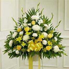 Standing floral spray with white and yellow flowers and a yellow ribbon