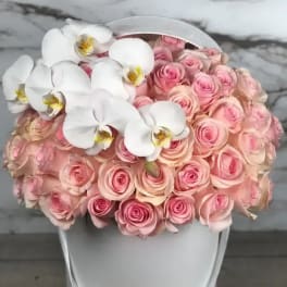 Pink roses with white orchids in a white hatbox