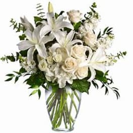 White lilies and roses arranged in a clear glass vase