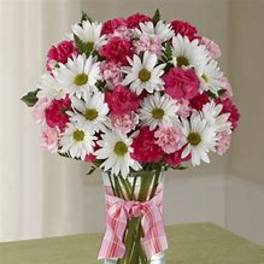 Pink and white daisy bouquet in a clear glass vase with a pink ribbon