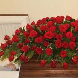 Large casket spray of red roses on a wooden casket