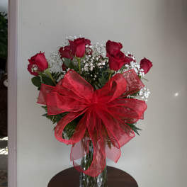 Red roses in a glass vase with a large red bow