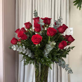 Red roses in a clear glass vase with silver eucalyptus