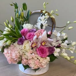 Round box arrangement of pink roses, orchids, tulips, hydrangeas and white orchids with green buds