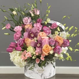 Mixed pink and peach floral arrangement in a marble-print hat box