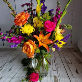 Colorful mixed bouquet in a clear glass vase with roses and lilies