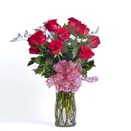 Bouquet of red roses in a clear glass vase with a heart ribbon