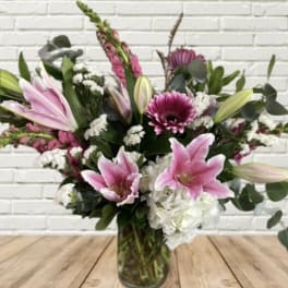 Pink lilies and mixed flowers arranged in a glass vase