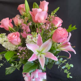 Pink roses and lilies in a glass vase with a pink ribbon