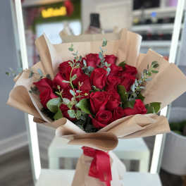 Bouquet of red roses wrapped in beige paper with a red ribbon