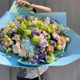 Large pastel bouquet with roses, carnations, and daisies wrapped in blue paper