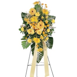 Yellow floral standing spray on an easel with ribbon