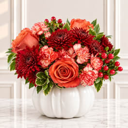 Orange and red floral arrangement in a white vase
