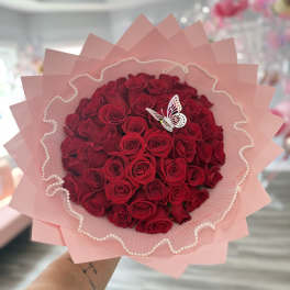 Bouquet of red roses wrapped in pink paper with a butterfly decoration