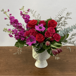Red and pink flower arrangement in a white vase