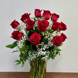 Red roses arranged in a clear glass vase with baby's breath