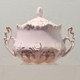 A pale pink decorative lidded bowl with ornate handles