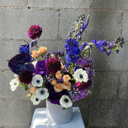 Purple and white floral arrangement in a white vase