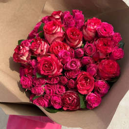 Bouquet of hot pink and red roses wrapped in brown paper