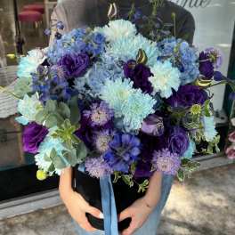 Large bouquet of blue and purple flowers with a ribbon tie