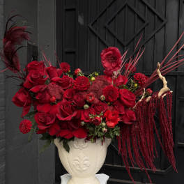 Red floral arrangement in a white pedestal vase