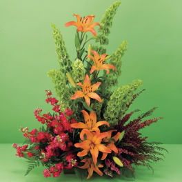 Orange lilies with pink and green floral spikes in a low arrangement