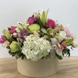 Mixed pink and white floral arrangement in a round beige box
