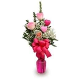 Pink rose arrangement in a small vase with a large ribbon bow