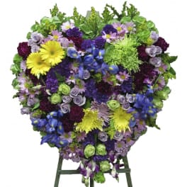 Heart-shaped floral spray with purple, blue, yellow, and green flowers on an easel