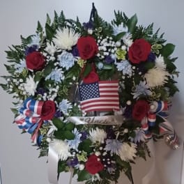 Heart-shaped floral wreath with red roses and an American flag