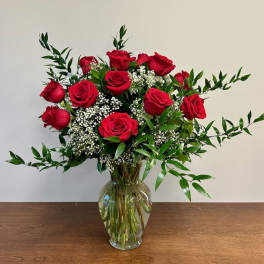 Red roses arranged in a clear glass vase with white filler flowers