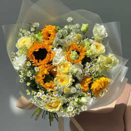 Bouquet of sunflowers, yellow roses, and white daisies wrapped in clear paper