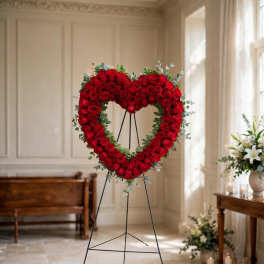 Heart-shaped red rose wreath on a stand in a bright room