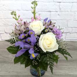 White roses and purple flowers in a glass vase